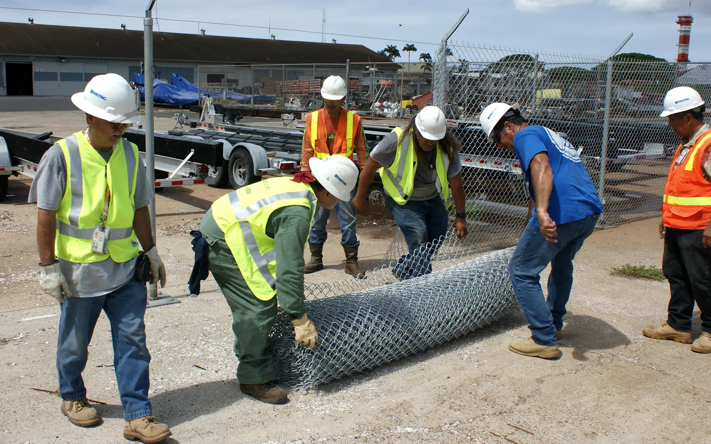 Fence crew unrolling chain link fabric on a commercial jobsite